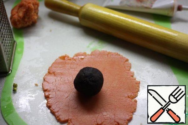 Add the dye to the marzipan.
Roll out the dough 2 mm thick.
Wrap each ball. Remove the excess.