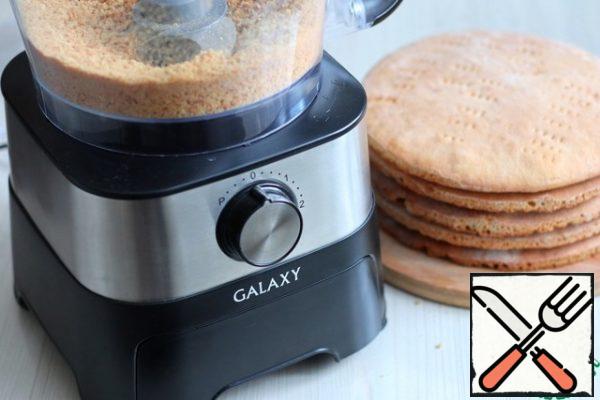 One of the cakes is crushed into small crumbs using a food processor.