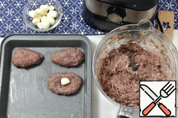 With wet hands, divide the minced meat into medium-sized tortillas. Place a mozzarella ball in the middle of each tortilla and form an oblong tortilla, making one edge thinner and the other thicker.