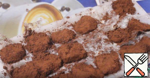 After 5 minutes, we get them out, they are soft and sticky, it is convenient to roll them in cocoa powder. Then put it back in the refrigerator for 20 minutes.