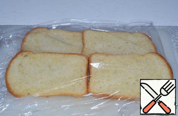 Place the slices of toasted bread on the film, slightly overlapping each other. Roll it out with a rolling pin.