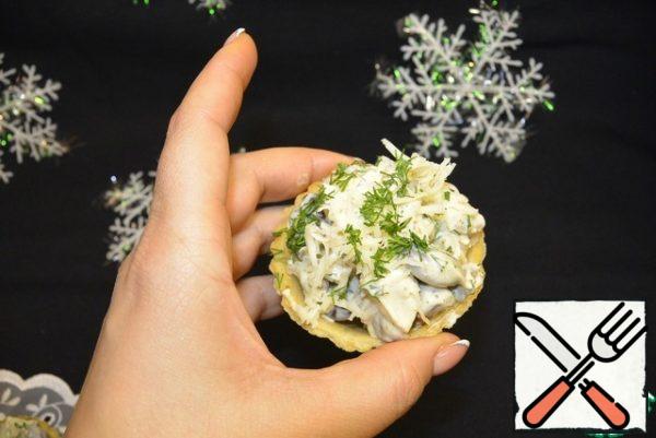 Fill the tartlets with salad. Garnish with grated cheese, chopped dill and roasted pine nuts.