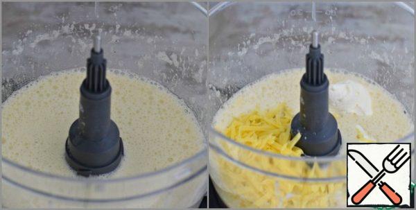 Using a food processor or mixer, beat the eggs. The egg mass should increase in volume and become lush.
Add sour cream and 50 grams of grated cheese to the eggs. Season with black pepper. Mix until smooth.