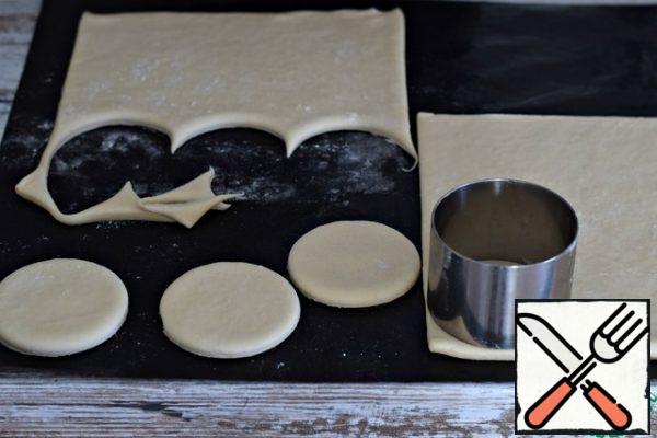 Prepare the finished puff pastry for use according to the instructions on the package. That is, defrost and let " come up" in the heat.
Using a cookie cutter , a small-diameter serving ring, or an ordinary glass, cut out round pieces of dough.