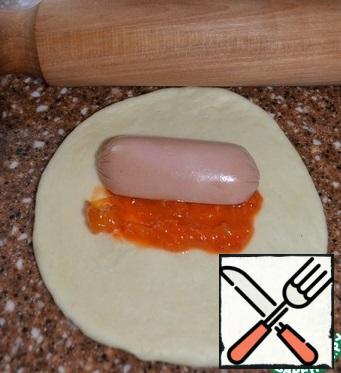 Roll out each bun,
put 1 tsp of sauce and half a sausage (or sausage) on it.
Pin it on top.
