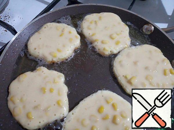 Put the future pancakes on a preheated frying pan with a small amount of sunflower oil with a spoon.