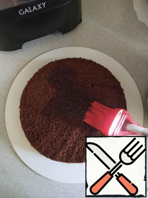 For the syrup, combine the water with sugar and bring to a boil. Remove from the stove and cool.
Start assembling the cake. Put the chocolate cake and soak with sugar syrup.