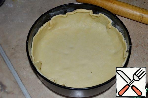 Grease the bottom of the mold with vegetable oil. A large piece of dough is rolled out so that it is larger than the shape itself.