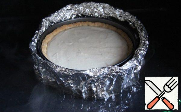 Cheesecake bake in a water bath. To do this, place the form with the dessert in a container filled with water. If your form is detachable, like mine, then you need to wrap it in foil.