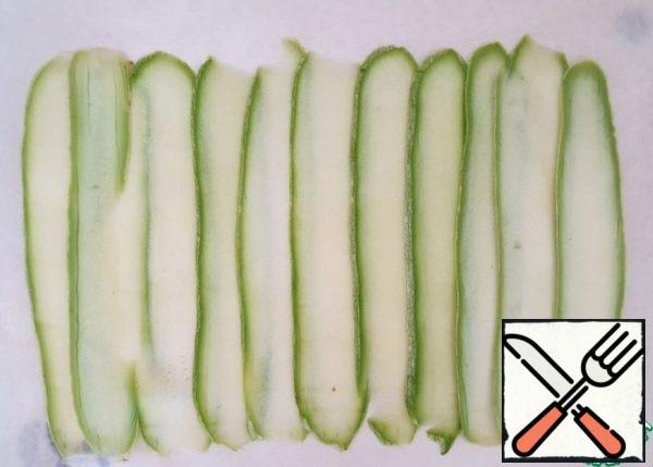Cut the zucchini into thin long plates. Spread out on a sheet of parchment. Sprinkle with a small amount of salt, so that they are slightly limp.