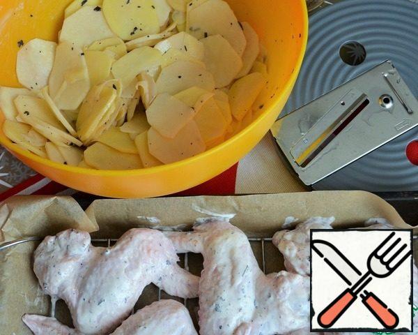 Place the wings on the grill, add salt to the potato slices, dip them into the marinade of the wings and mix.