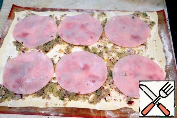 Roll out the dough, grease with mayonnaise, put the filling squeezed from the juice, put slices of ham on top.