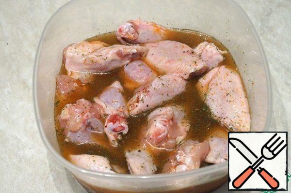 At the wings, cut off the last phalanges. Cut the wing in half. Put the wings in a deep container. Pour cold water, add spices, and mix. Close the container tightly with a lid and put it in the refrigerator for 12 hours.