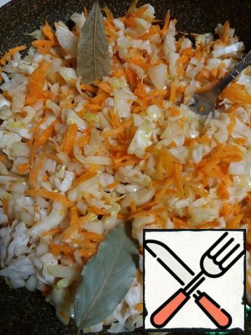 Start preparing a multi-component filling. To do this, we will chop the peeled vegetables: finely chop the cabbage, cut the onion into small pieces, and grate the carrots on a large grater. Now send them to the oil heated in the pan (5 tbsp), add the Bay leaf and salt, and put out for 25 minutes.