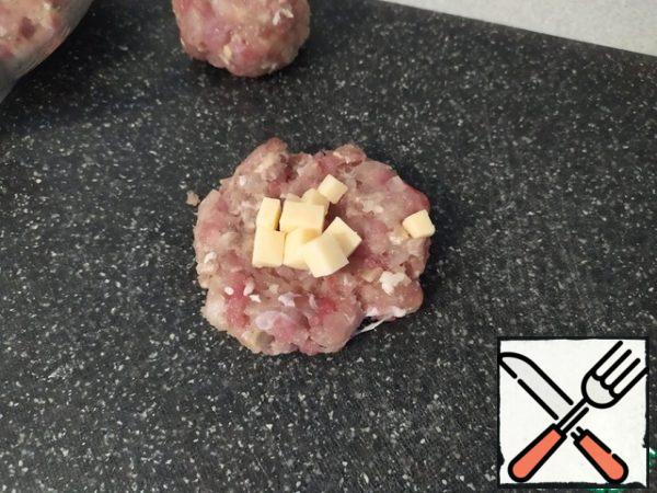 Take some minced meat and form a flatbread. In the middle of the tortilla, put the sliced cheese. Form a meatball.