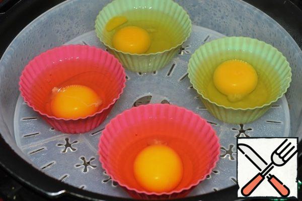 In silicone molds, break the eggs. As soon as the water boils, put them on the grill of the steamer. Cook for 8-10 minutes with the lid closed.