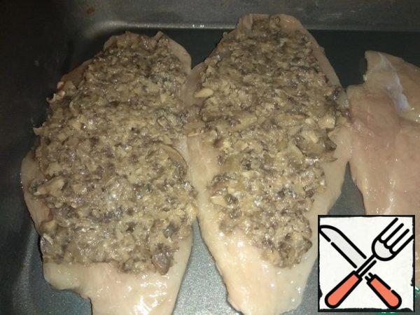The chops were transferred to a greased baking dish. I put mushroom caviar from champignons on each piece. Sprinkle with grated cheese.