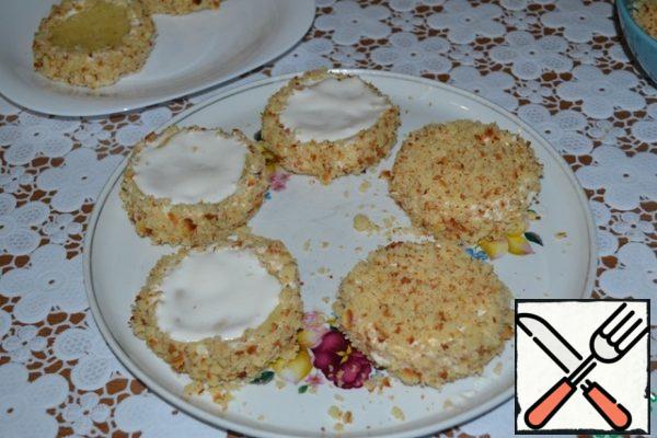 Now, dip the sides of the cakes in cream and roll them in crumbs. Put on a platter, smear with cream.