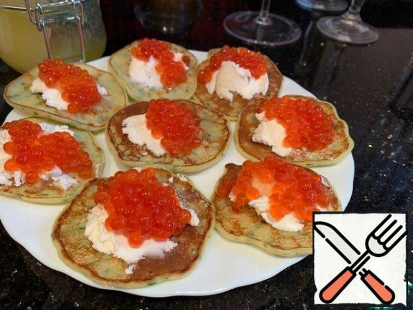 Put 1 tsp of curd cheese and red caviar on each pancake.