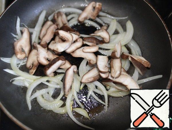 Heat the oil in a frying pan , lightly fry the onion, put the chopped mushrooms.