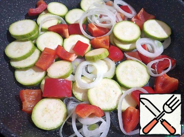 In a large frying pan, heat the olive oil and fry the peppers, zucchini and onion over high heat, stirring occasionally.