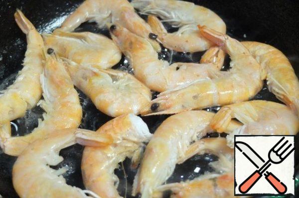 Frozen prawns spread on a hot pan. when the ice melts, drain the water. Add a little oil and fry on both sides until tender.