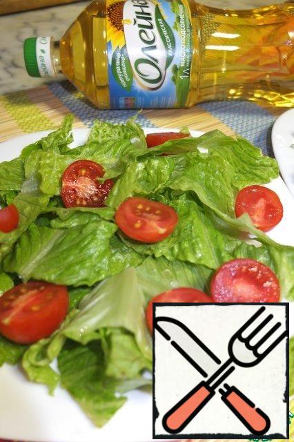 Cut the cherry tomatoes into halves and spread them on the lettuce leaves.