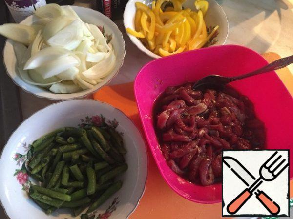 While the beef is marinating, prepare the vegetables. Cut the pepper into strips. Onion in large straws. My beans are frozen. Washed and drained all the water.