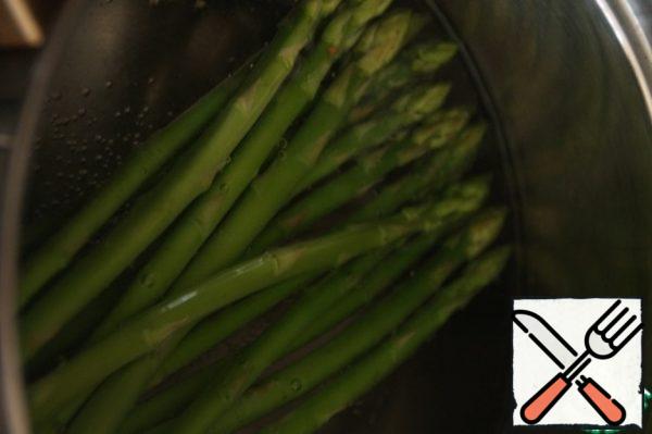 Wash the asparagus and put it in boiling water for 3 minutes. Prepare a container with ice water and a couple of ice cubes, immediately after 3 minutes, move the pan with asparagus to an ice bath.
This way the asparagus will remain green and crisp.