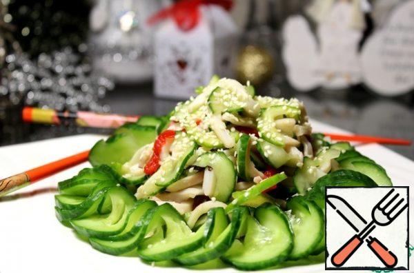 Get the squid with vegetables, squeeze. Cucumber, cut into a garland, slightly squeeze, put on a dish ring, pour a little soy sauce, in the middle put the squid with vegetables. Sprinkle with fried sesame seeds.