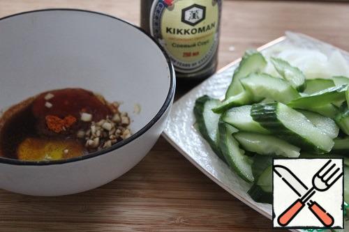 Cut the cucumber diagonally into not very thin slices, and the onion into thin half-rings.
For the sauce, mix the chili, soy sauce, sesame oil, powdered sugar, vinegar, salt, and pepper.