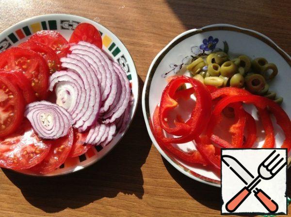 Onions, tomatoes, olives, and pepper cut into circles.