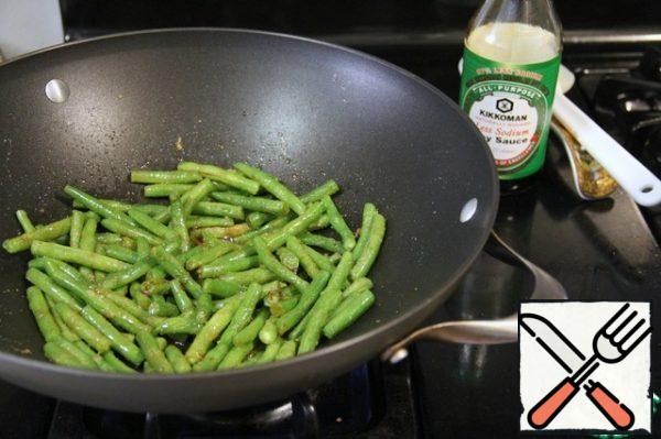 Green string beans are washed, cut in half, put in a deep pan and stew in a pan with vegetable oil. After 5 minutes, add the garlic powder and soy sauce and simmer with the lid closed for another 5-7 minutes until ready. If necessary, you can add a little water.
