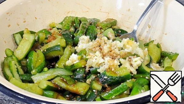 Add sweet and sour cucumbers, ground sweet paprika, fried sesame seeds, crushed garlic and bitter pepper.
Pour vegetable oil into a frying pan, heat until a light haze appears, remove from heat and let cool slightly for 1-2 minutes. Pour the heated oil over the spices.