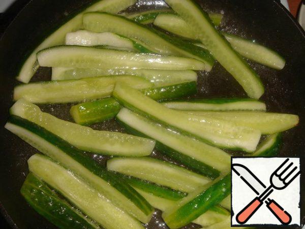 Lightly squeeze the cucumbers and fry in hot vegetable oil for a few minutes. Squeeze the garlic clove through a press and fry for a few more minutes.