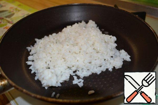 Heat the vegetable oil in a frying pan. Lay out the rice and fry over high heat, stirring for 3-4 minutes.