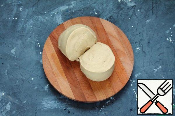 Gradually pour in the remaining flour and knead a smooth, elastic dough that does not stick to the hands and surface. If necessary, you can add up to 30 g of flour and knead again. Put the dough in a bowl, cover with cling film and leave for 10 minutes. Stir for another 1 minute and leave for 30 minutes.