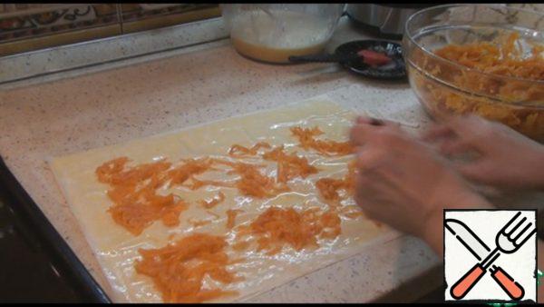 Cover with the second sheet of dough and again lubricate, cover with the third sheet and again smear with filling. On top, spread the grated pumpkin not a thick ball over the entire surface of the dough.