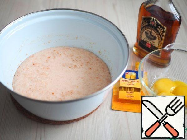 As soon as the milk-yeast mixture increases in size and a cap of small bubbles is formed on the surface, add 1 tablespoon of cognac to the mixture, add 1/2 teaspoon of vanilla essence, add 3 egg yolks. Beat the mixture well with a fork.