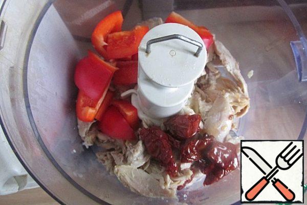 The flesh of cooked chicken, pieces of sweet pepper and dried tomatoes are placed in the bowl of a blender