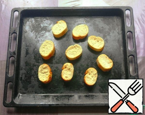 Leave 6 slices of baguette, put the rest on a baking sheet and sprinkle with olive oil.
We send the baguette to the oven. The baking time depends on the oven. You should get toasted croutons, but not hard crackers.
You can fry in a frying pan, but you will need to flip the pieces once.