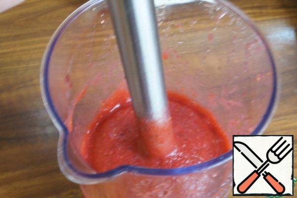 Thawed strawberries using an immersion blender to turn into a puree.