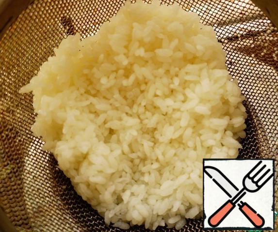 Half-cooked rice is thrown into a colander, washed with cold water to stop the cooking process.