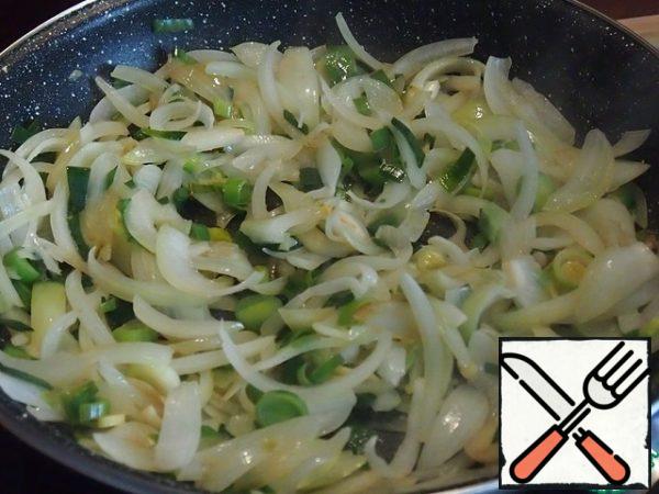 In the heated sunflower oil, fry the onion and leek until soft.