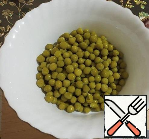 We throw the green peas in a colander, wash and let the liquid drain.