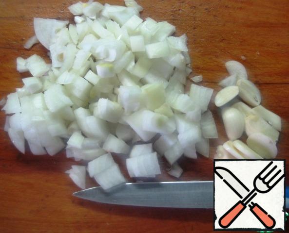 Cut the onion into small cubes. Garlic-plates.Heat a little vegetable oil in a frying pan and fry the onion and garlic over medium heat until Golden, not forgetting to stir.