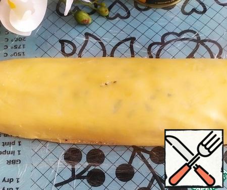 Roll the cheese cake into a tight roll. Start from the bottom, gradually separating the layer from the film. The formed cheese roll is tightly wrapped in plastic wrap and put in the refrigerator for 1 hour.