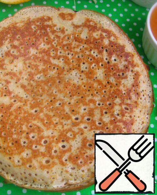 As soon as the edges of the pancake are browned, turn it over and fry the second side. Then remove the pancake to a plate and grease with butter.