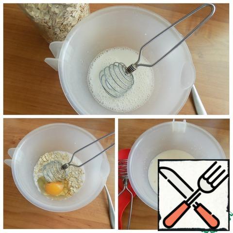 Make the dough. Pour sour milk (kefir) into a bowl, add soda to it, stir and wait for the reaction. In sour milk, the soda will be extinguished. Put the sugar, egg and oatmeal. Connect the whisk. Push the mixture aside. Let the flakes swell. In the meantime, we'll do the filling.