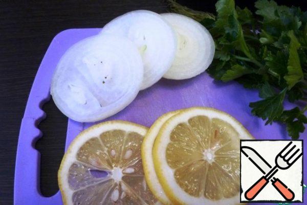 Meanwhile, cut the onion and lemon into thin rings. 3-4 rings are enough. Rinse the parsley and dill with water.
Onions, lemon and herbs will be placed in the belly of the carp for flavor and juiciness.